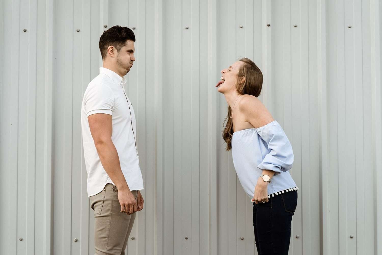 A couple pull funny faces but demonstrate how soft complementary colours work well to wear on their engagement shoot
