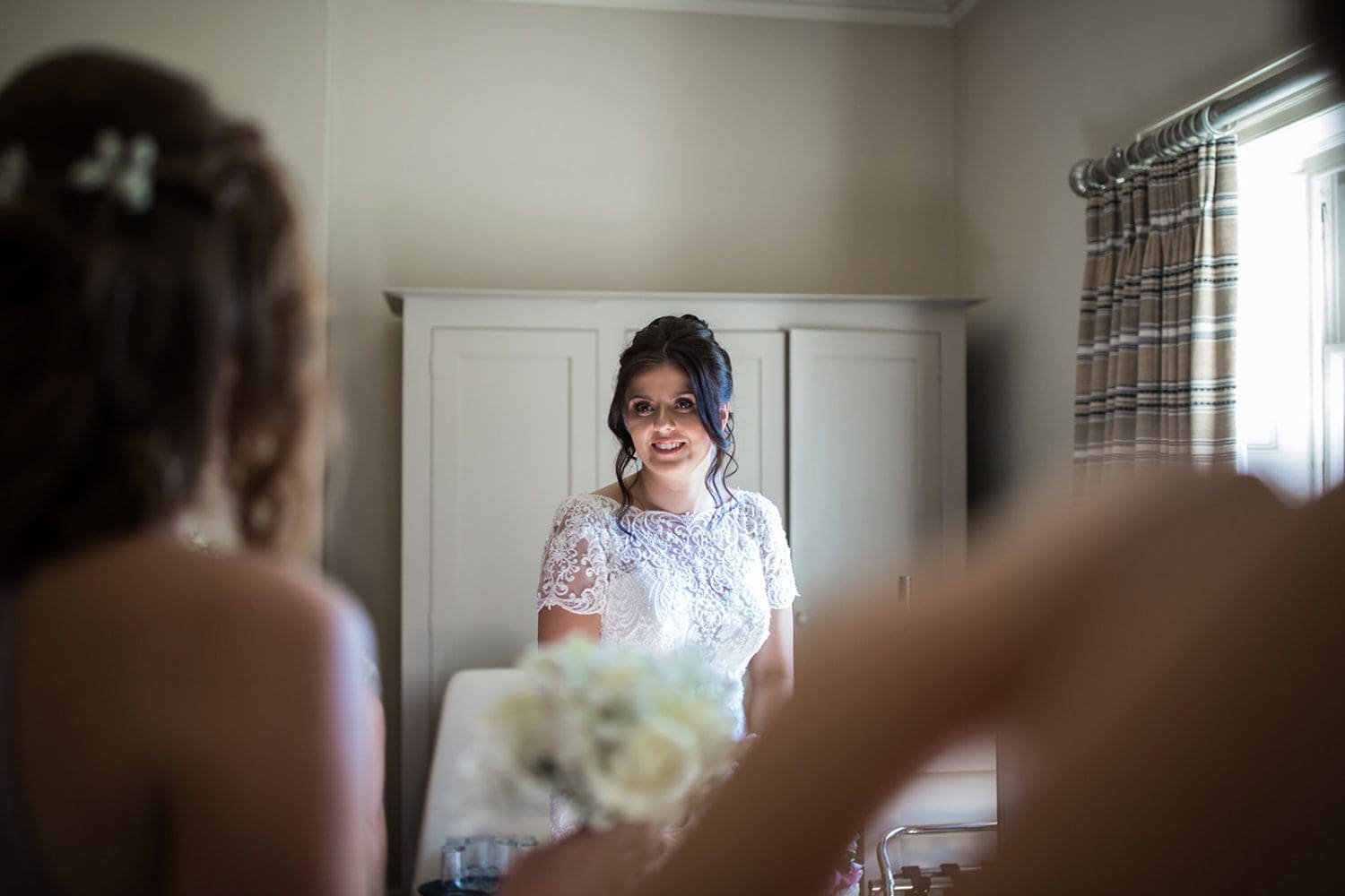 bride is seen in her dress for the first time by her bridesmaids at her suffolk wedding in kesgrave hall 