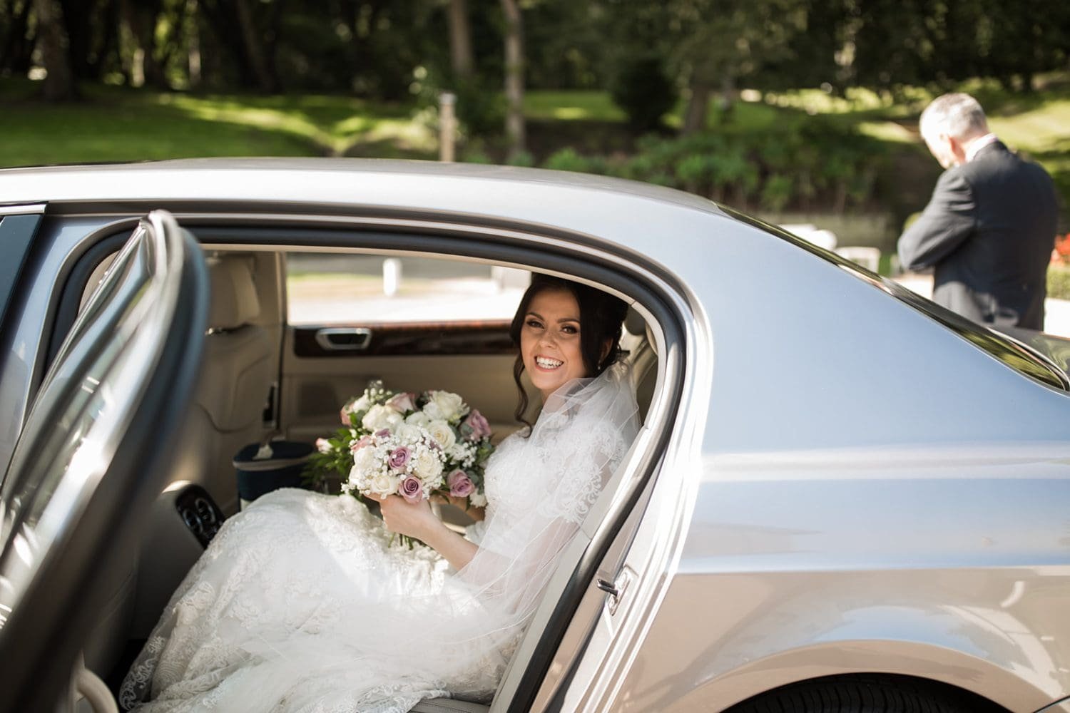 bride arrives at church for her wedding in a silver car 