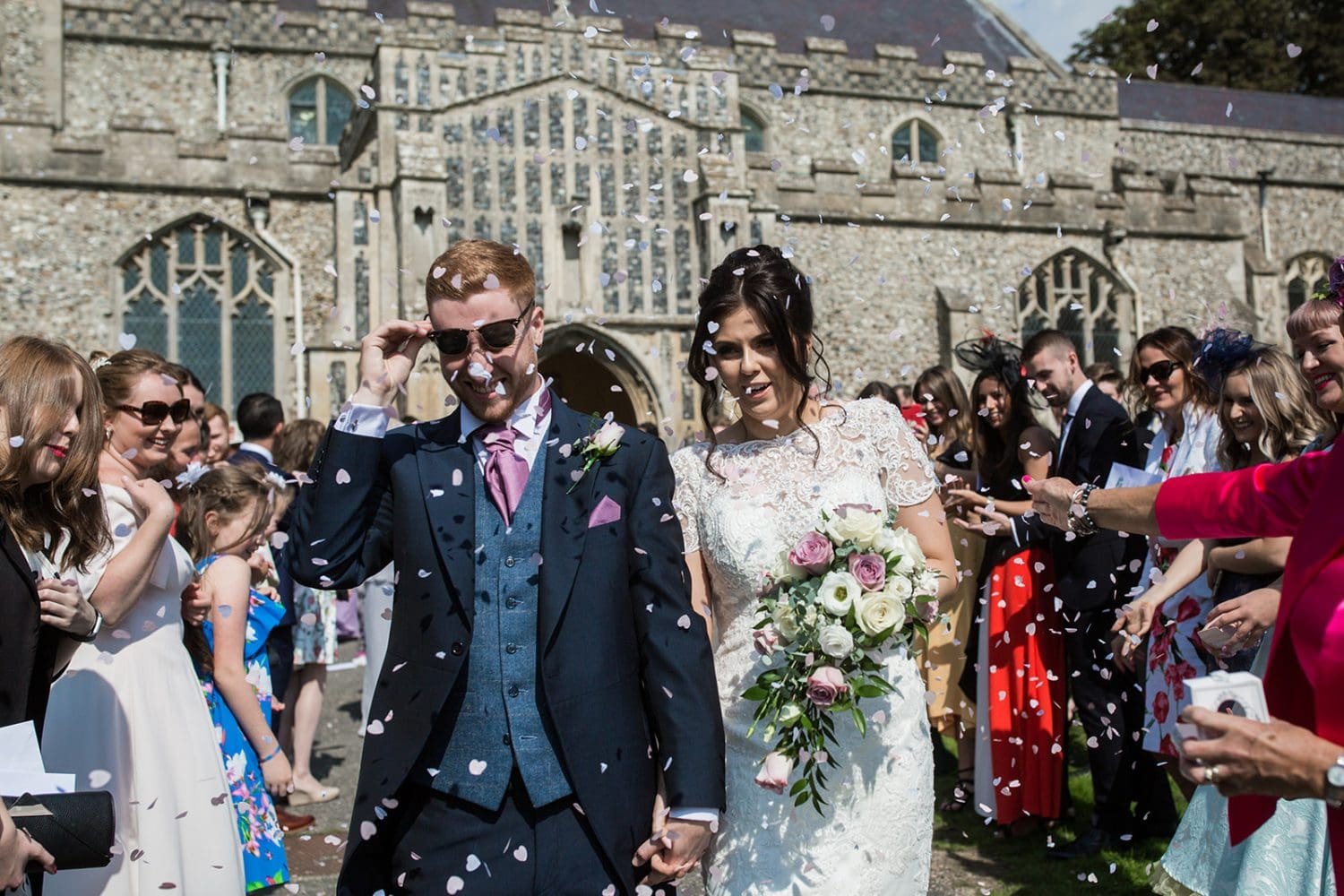 confetti overwhelms a newly married couple at their suffolk church wedding
