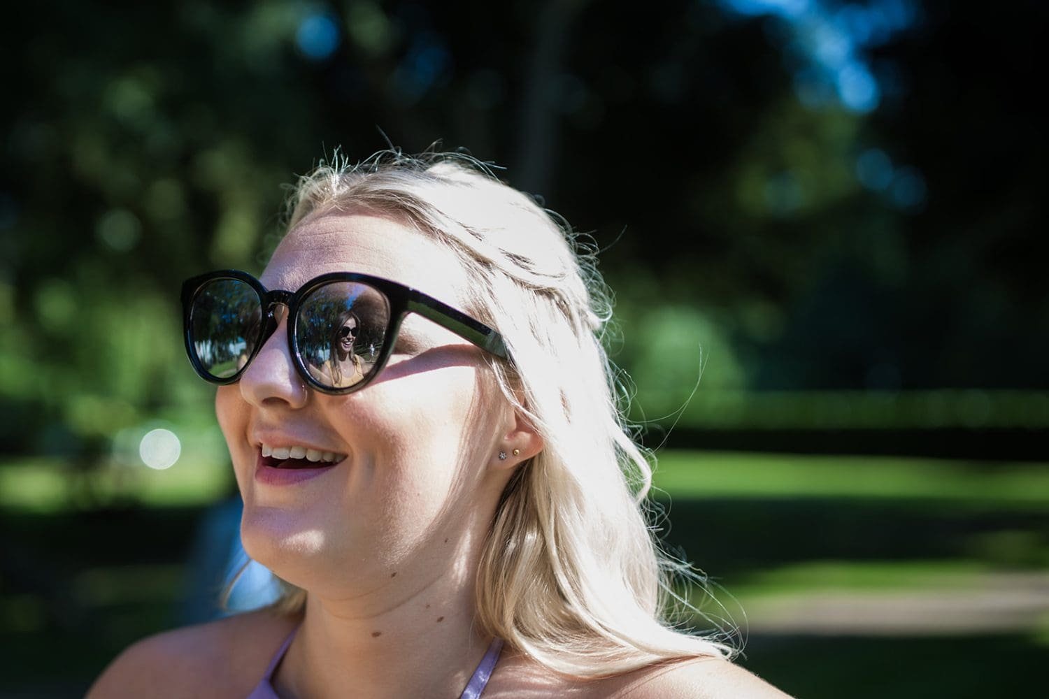 guests laughs while her friend is reflected in her sunglasses