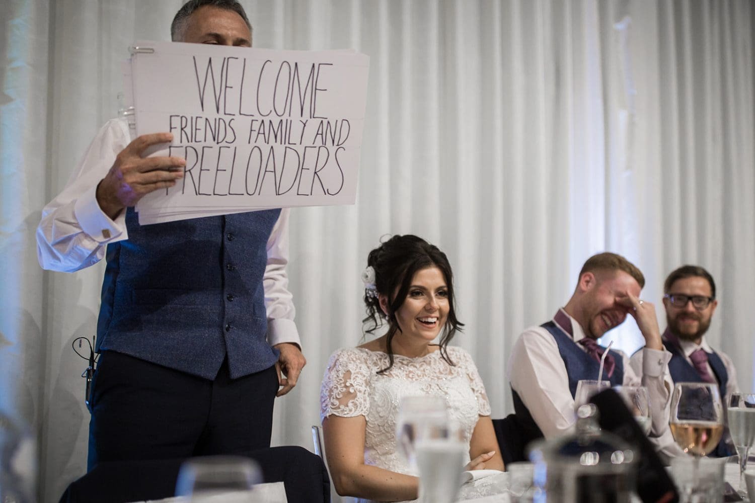 bride laughs as dads speech at the hangar kesgrave in this suffolk wedding photo. Milsoms Kesgrave Hall wedding