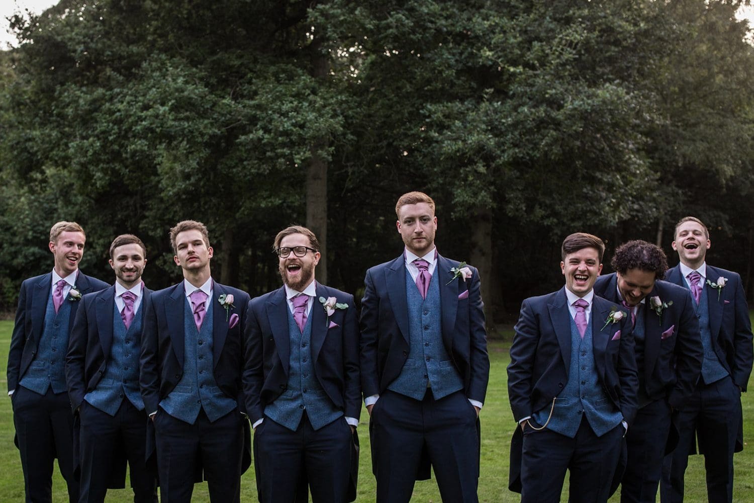 groomsmen laugh as bridesmaids walk past during formal photos at a suffolk wedding 
