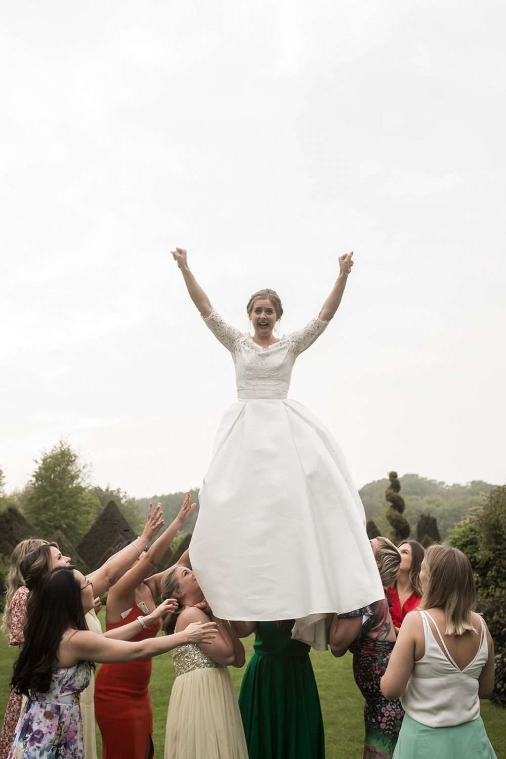 bride is elevated in the air by her friends and bridesmaids during her wedding reception