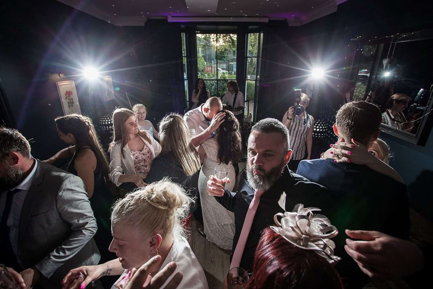 Bride and Groom embrace during their first dance whilst listening to wedding duo Cupids Wish and surrounded by their family and friends at The Georgian Townhouse wedding in Norwich Norfolk.