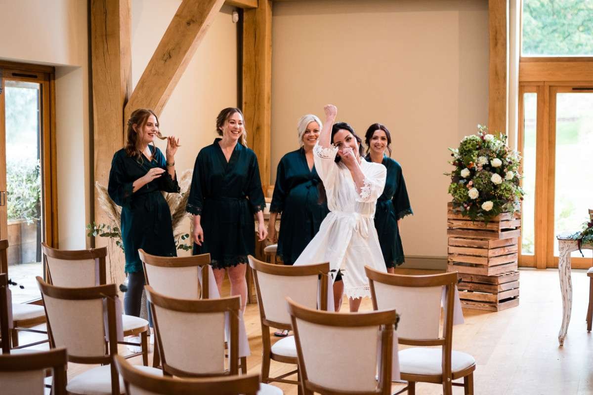 Bride and her bridesmaid pretend to be a pop group whilst in their dressing gowns and preparing for her Easton Grange wedding in Suffolk. 
