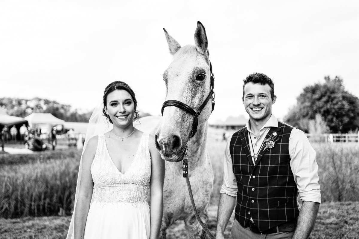  tipi wedding in suffolk the couple stand with their horse for a portrait