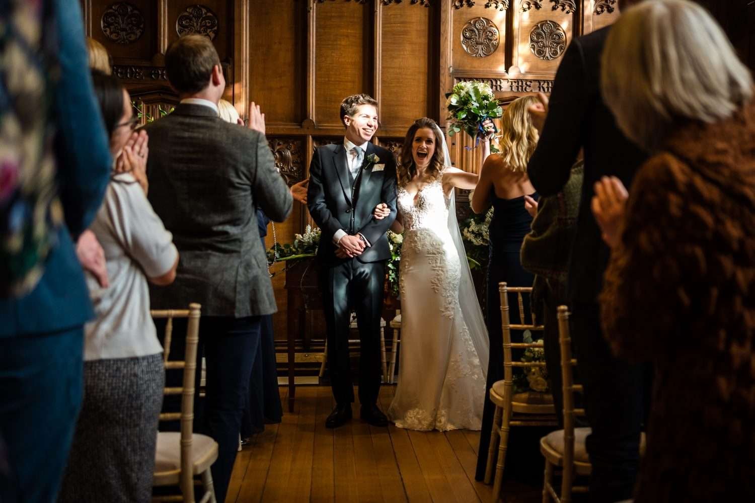 A newly married couple hold arms as their guests clap to congratulate them of the marriage at hengrave hall in suffolk