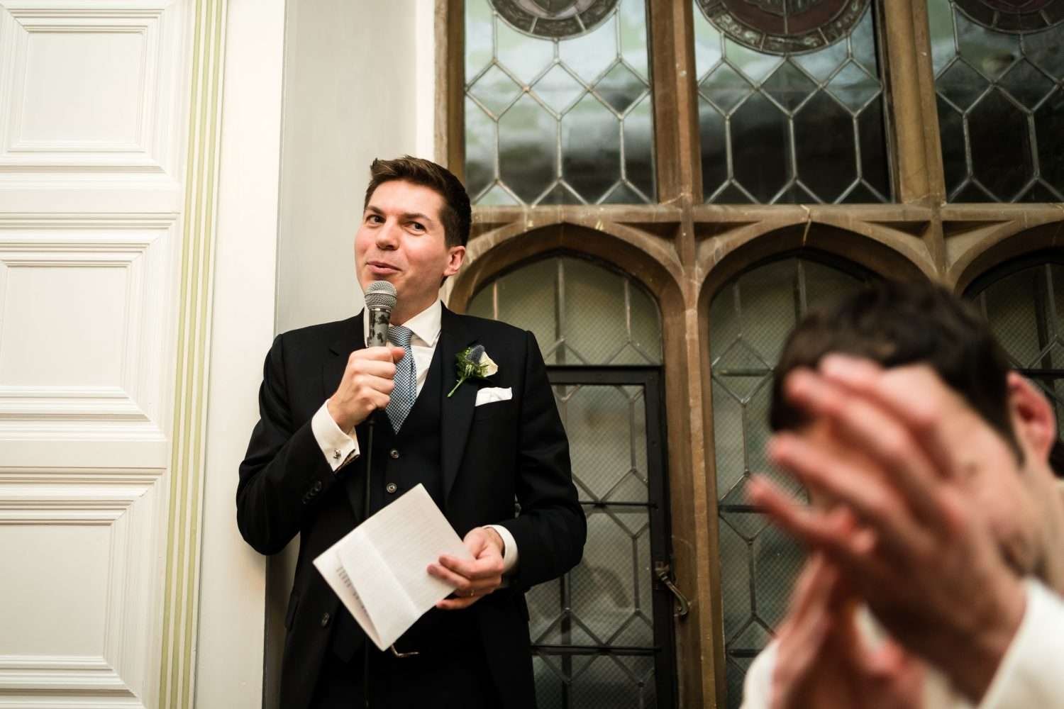 a groom smiles to applause given during his speech after his wedding breakfast