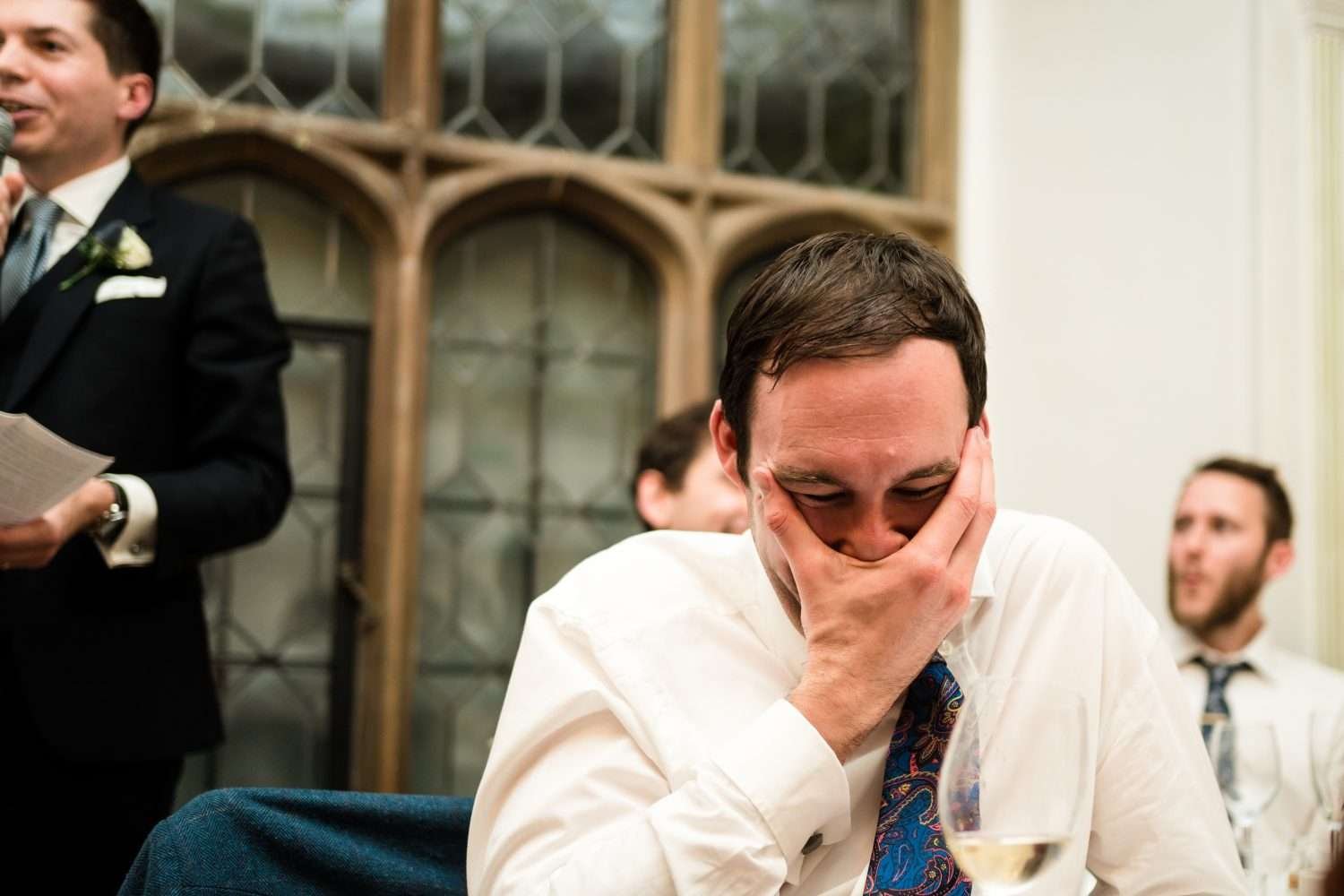 a guests grabs his own face whilst laughing at the grooms after dinner speech
