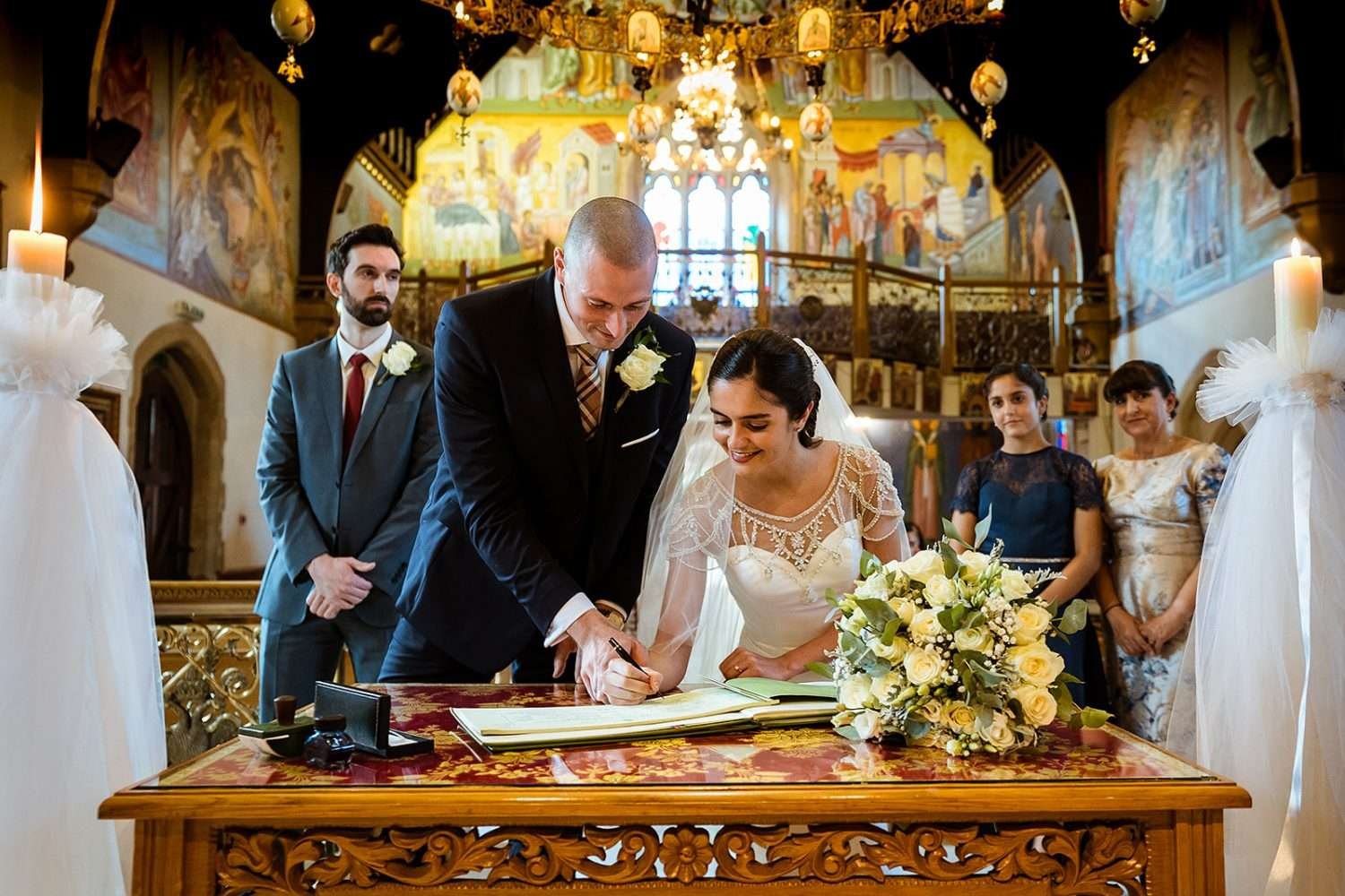 A couple sign the register for thier wedding in a greek orthodox church. The photo is included ofr a blog on 'how wedding ceremonies work' and is an example of one of the key features of a wedding ceremony. 