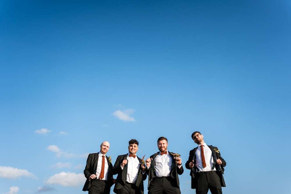 Groom and his attendance have fun in a group photo at a Fishley Hall wedding in the Norfolk Broads. 