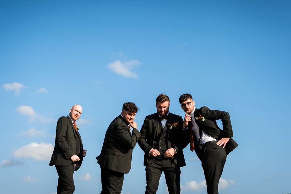 Groom and his attendance have fun in a group photo at a Fishley Hall wedding in the Norfolk Broads. 