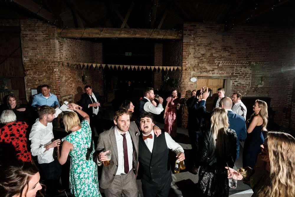 Groom enjoys dancing with his guests in the great barn at his Fishley Hall wedding