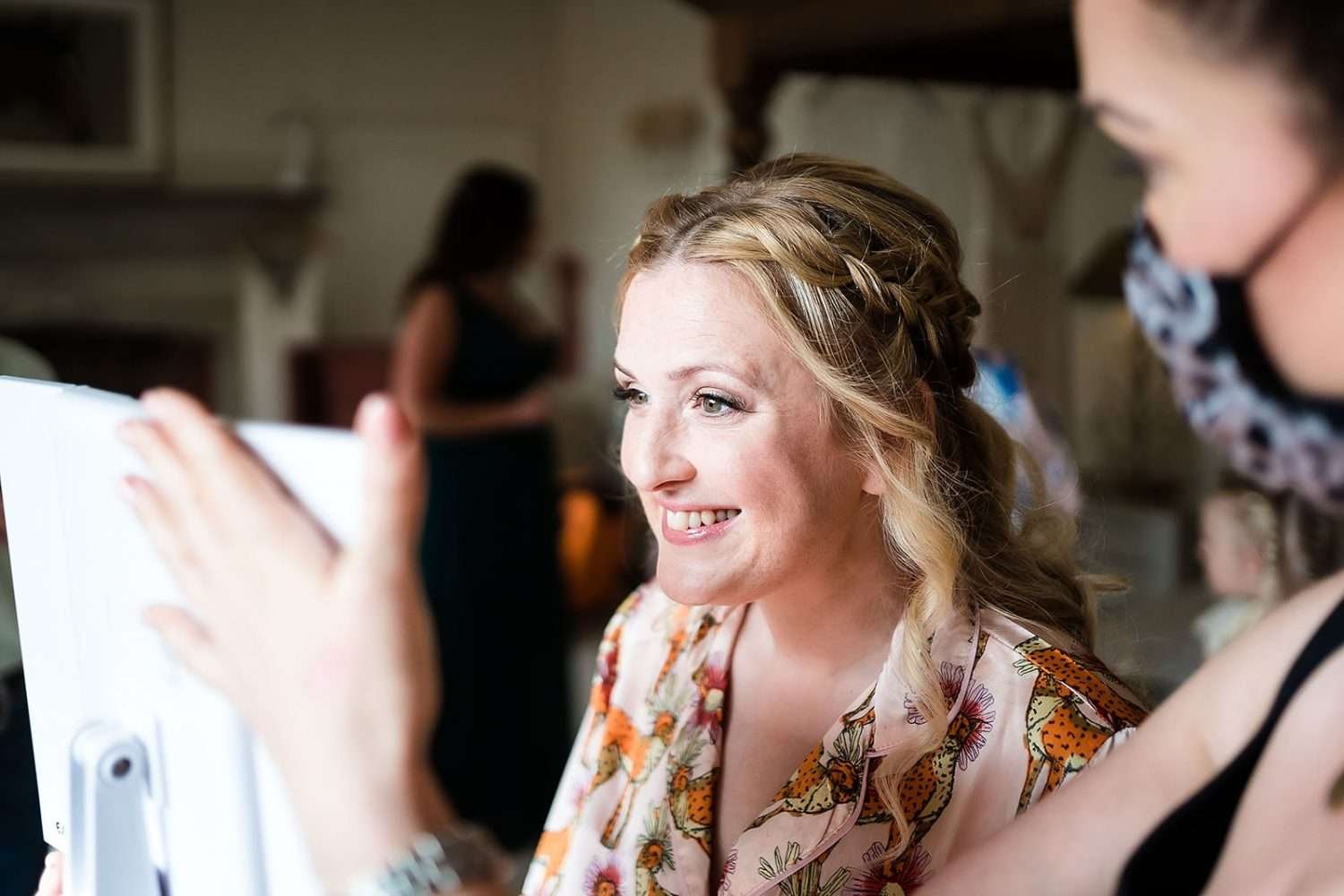 bride smiles while her make up is applied during getting ready at Bruisyard hall wedding venue in suffolk 