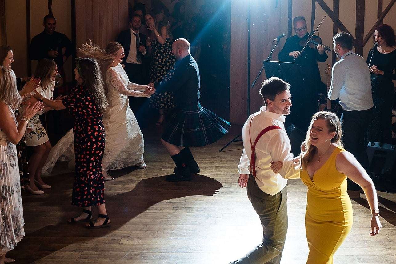Happy dancing to a ceilidh band at a Bruisyard Hall wedding 