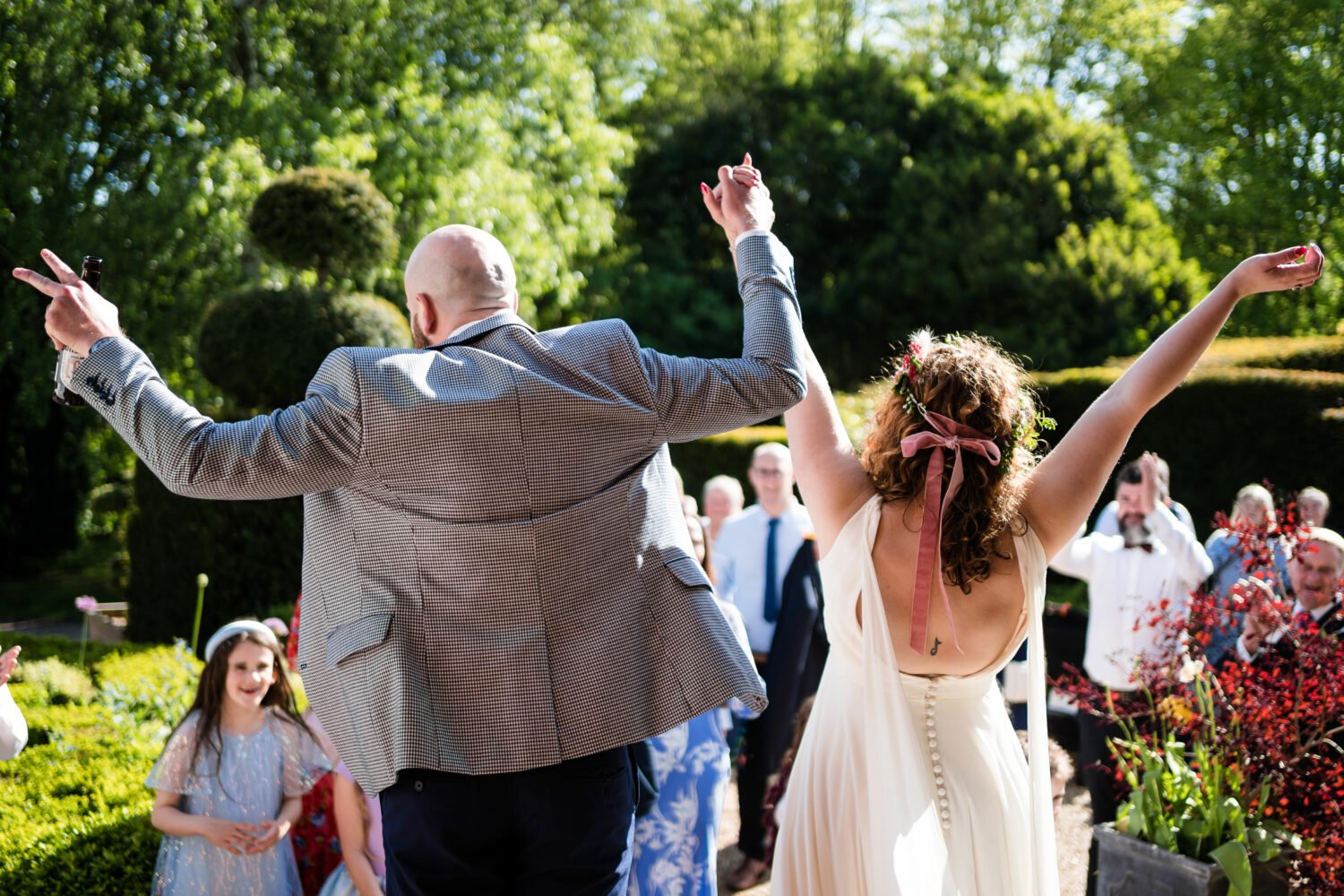 Couple cheer at their guests in the afternoon at their Chaucer Barn wedding in Norfolk 
