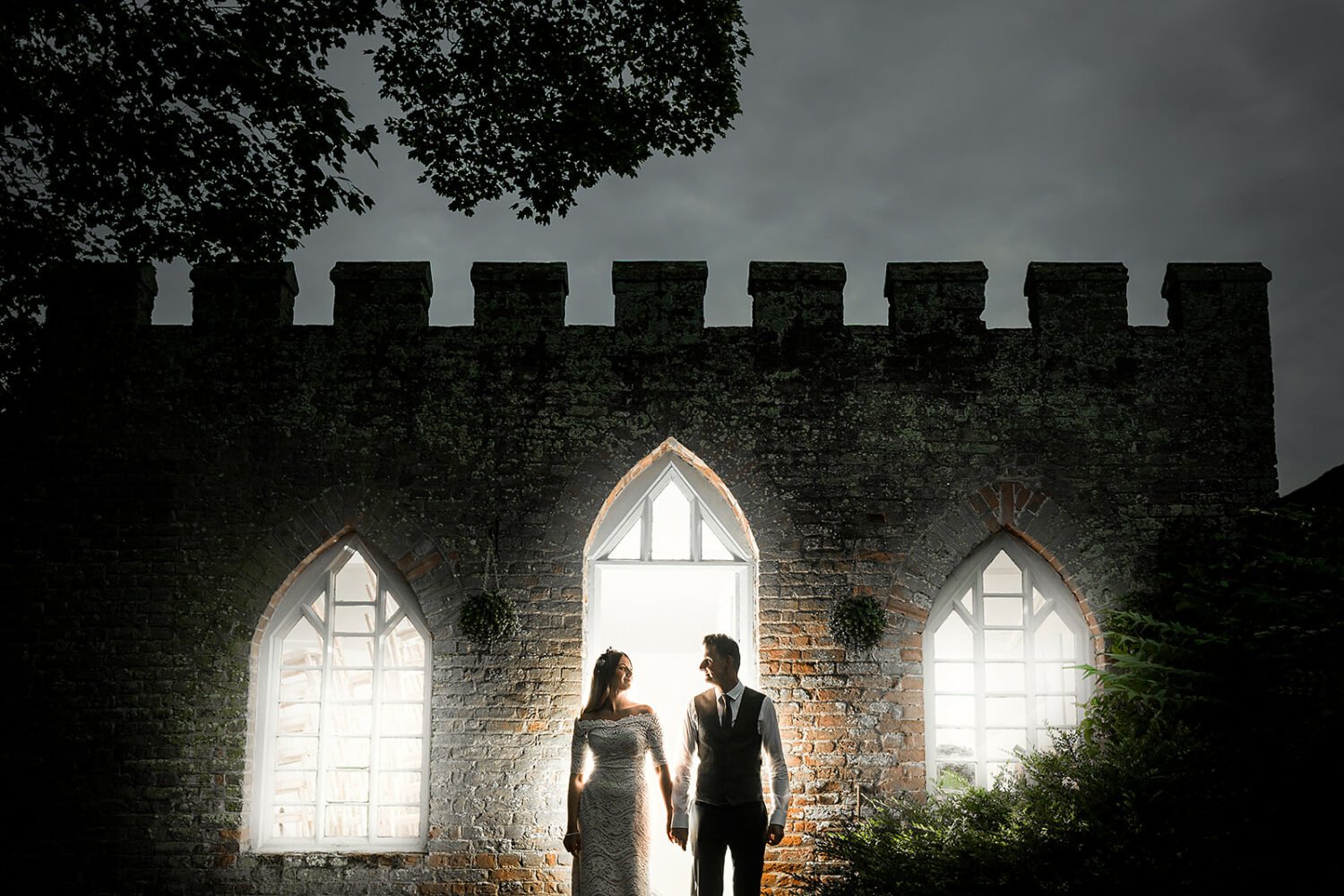 couple portrait in front of the castellated garden room at hockwold hall in norfolk 