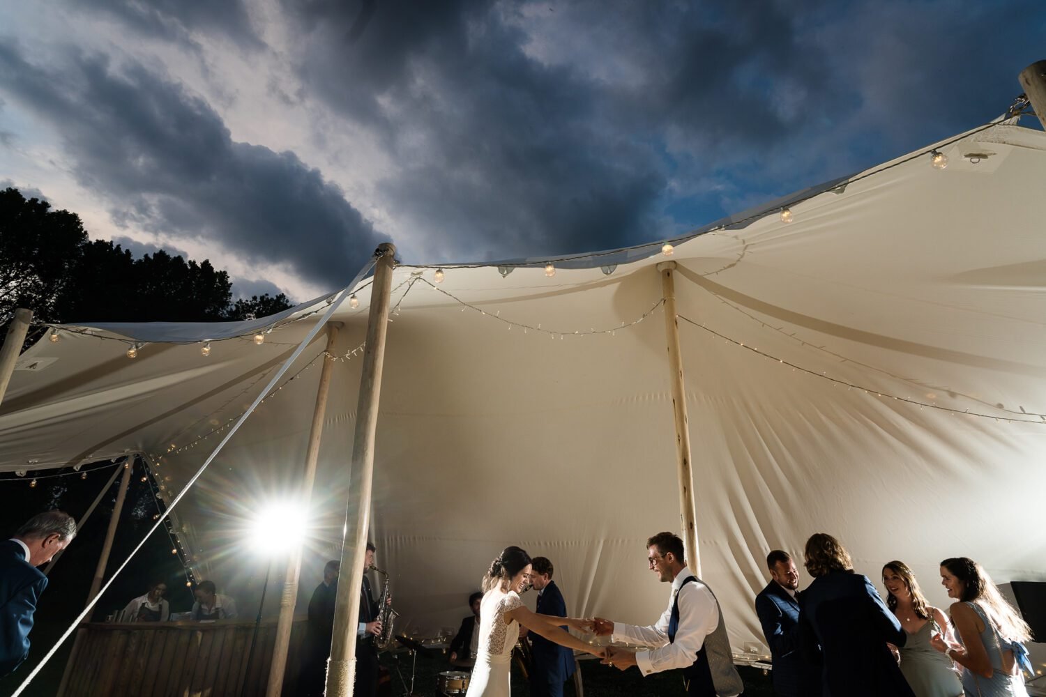 Bride and Groom dance in a stretch tent whilst the sky darkens over them